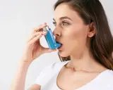 Frau mit Asthmaspray, das sie falsch anwendet. Die Anwendung ist nicht korrekt, was die Wirksamkeit beeinträchtigt.