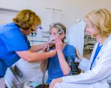 Ärztin und Pflegekraft helfen Patientin mit Lungenemphysem bei der Anpassung einer Beatmungsmaske. Medikamente sind Teil der Behandlung.