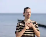 Mann mit geschlossenen Augen und Händen auf der Brust, genießt die frische Meeresluft. Eine asthma kur am meer kann Wunder wirken.