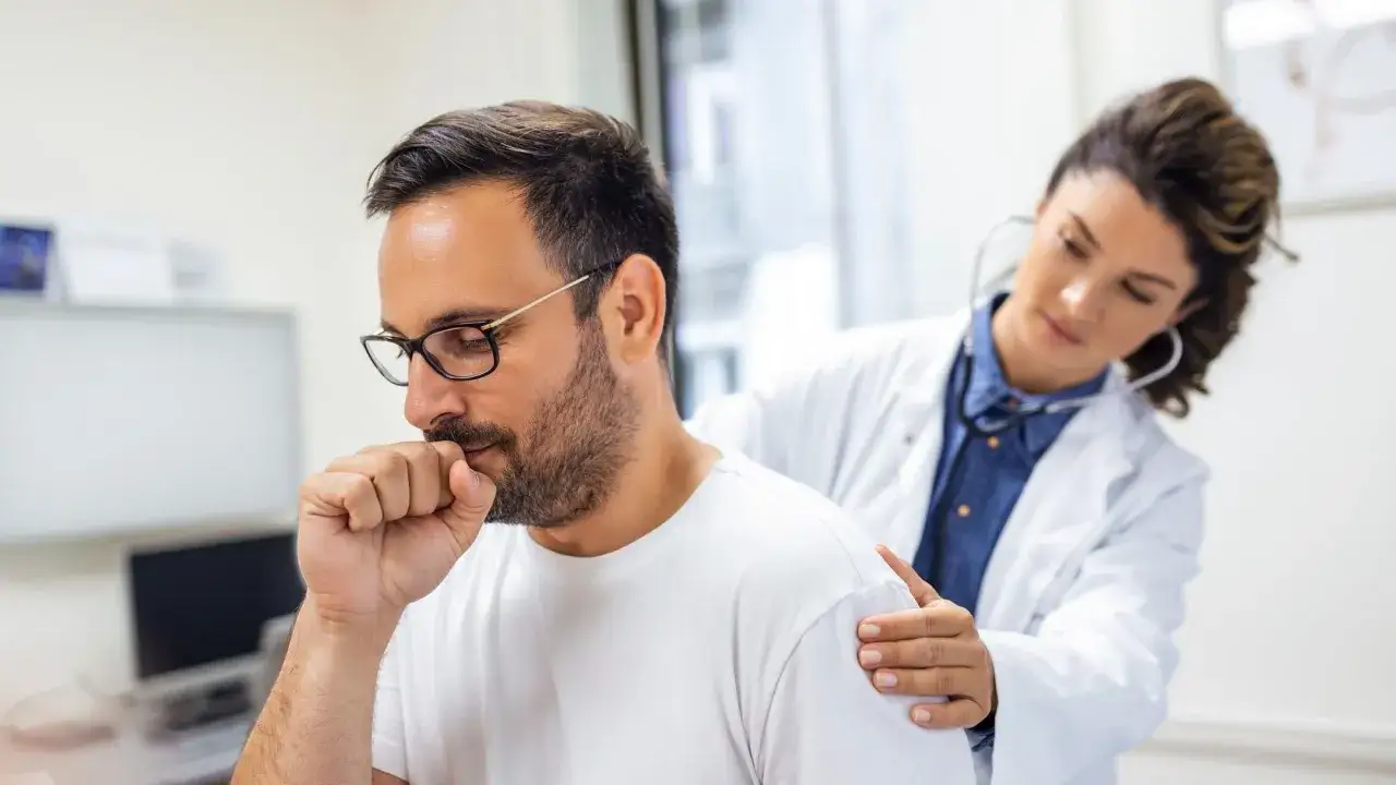 Mann hustet, Arzt hört Lunge ab. Bei Verdacht auf Asthma ist der Lungenfacharzt der richtige Ansprechpartner.