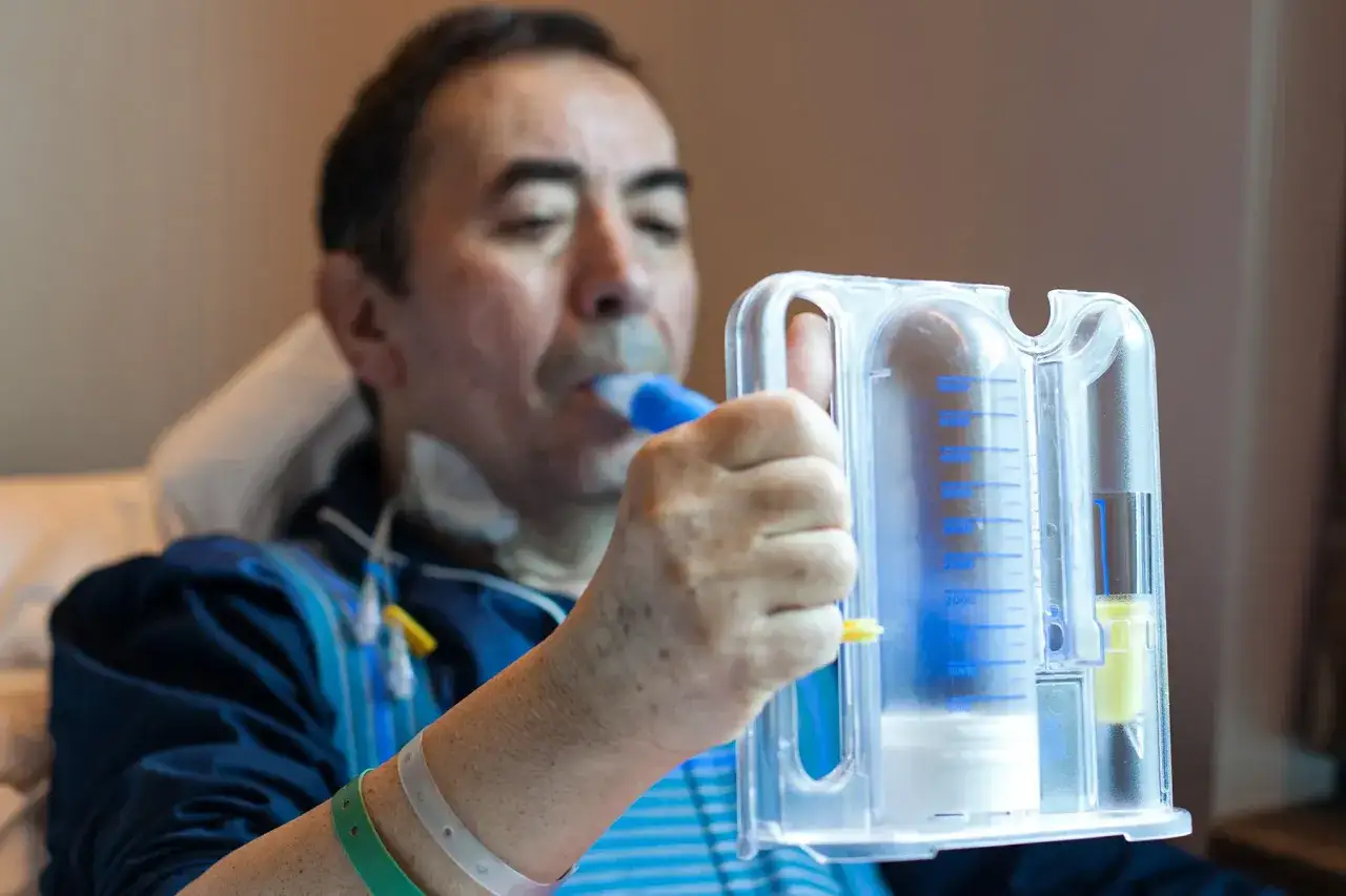Mann übt mit einem Spirometer, um zu lernen, wie inhaliert man richtig durch Mund oder Nase.
