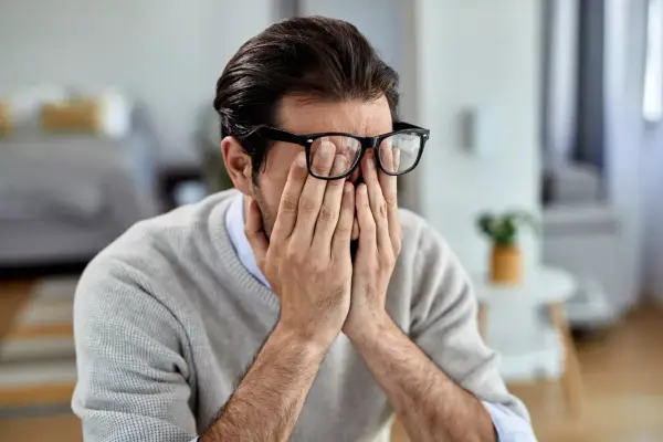 Mann mit Brille reibt sich die Augen, wirkt gestresst. Manche glauben, rauchen hilft gegen Stress, doch das ist ein Trugschluss.