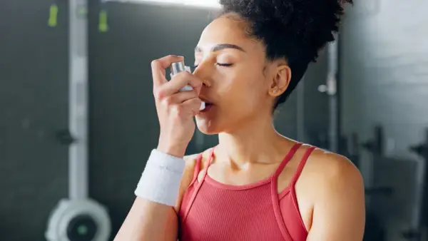 Frau mit Inhalator im Fitnessstudio. Sport bei COPD kann mit richtiger Vorbereitung möglich sein.