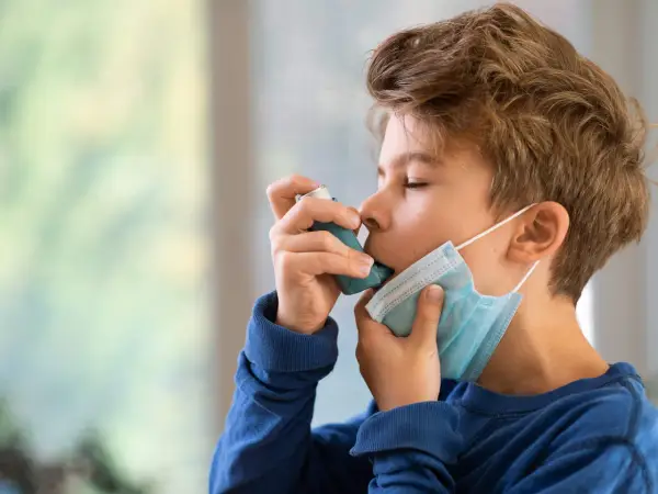 Junge mit Inhalator und Maske. Gute Behandlung beeinflusst die asthma lebenserwartung positiv.