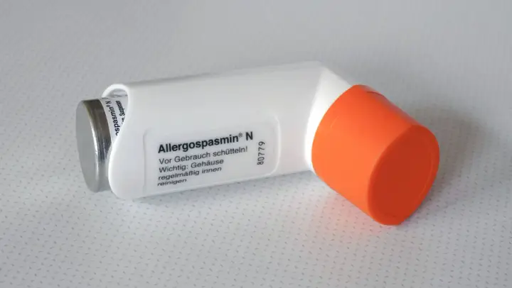 Ein weiß-oranger Inhalator, "Allergospasmin N" beschriftet, hilft bei allergischem Asthma.